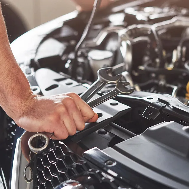 Mann holder skiftnøkkel ved bilmotor