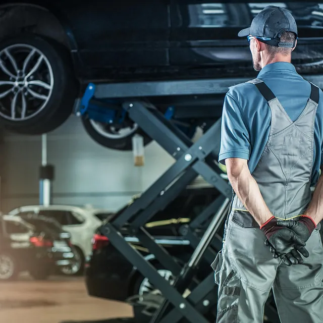 Mann i arbeidsklær foran bilder på verksted